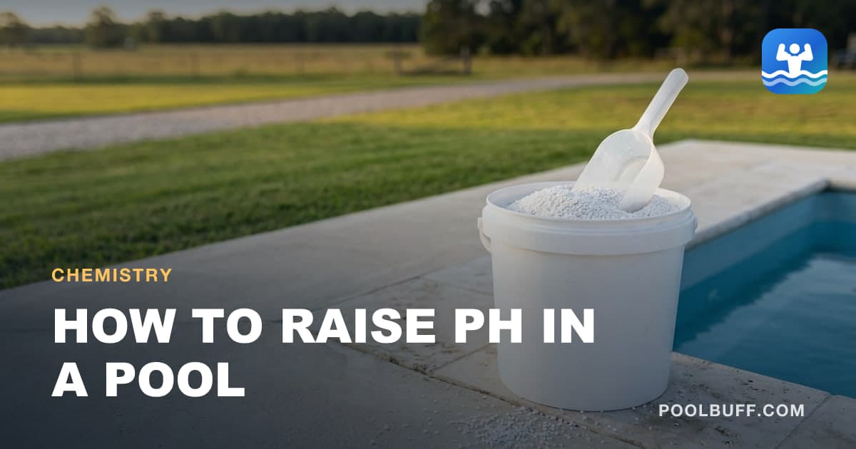 A white pail of coarse white granules with a clear scoop on concrete coping beside a blue pool, granules spilled on the stone and a lawn behind