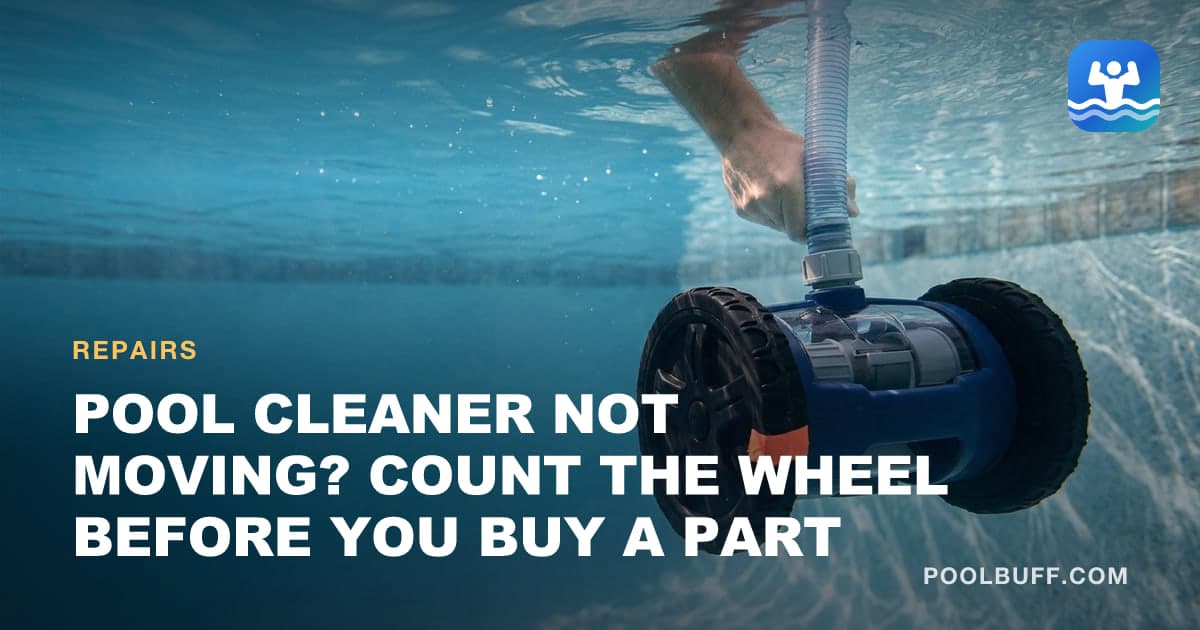 A hand holding a two-wheeled suction pool cleaner underwater by its ribbed hose, a short strip of orange tape on the edge of one black tire marking the turns to count
